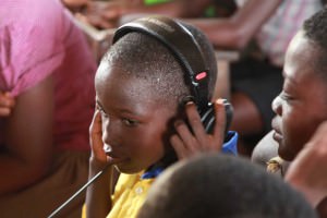 A student in Yamoransa listens to a live audio feed on headphones