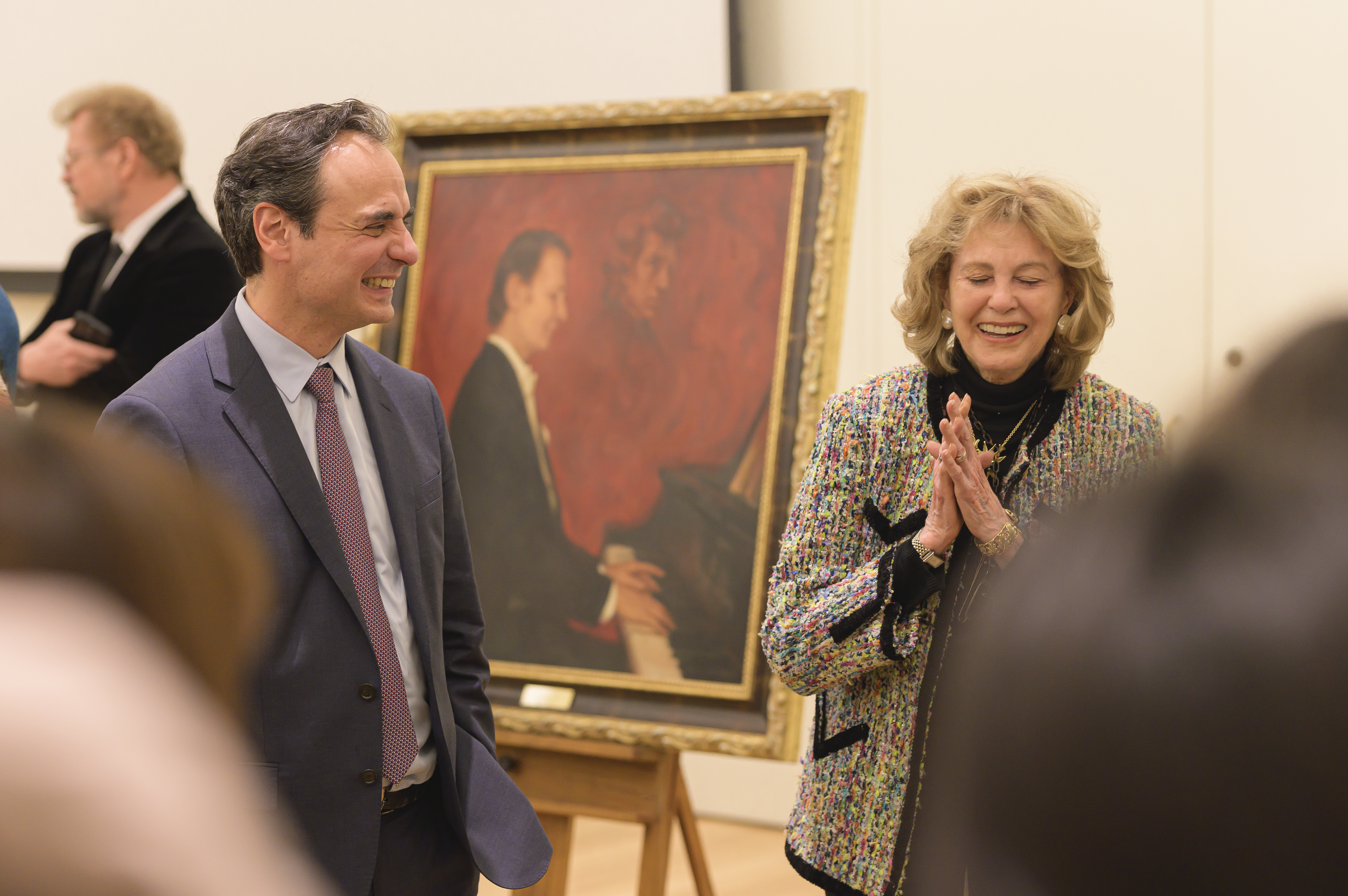 a man in a suit standing with a woman in tweed