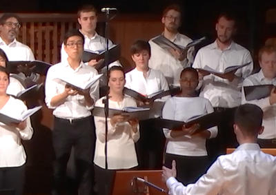 A conductor directing a choir at the Music Shed.